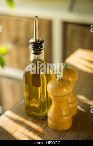 Set di macine di spezie e una bottiglia di olio d' oliva sul tavolo di legno Foto Stock