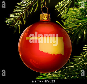 Una pallina rossa con la forma d'oro di Oklahoma appeso a un albero di natale isolato sul nero.(serie) Foto Stock