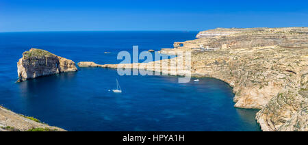 A Gozo, Malta - panoramica vista sullo skyline di Dwejra Bay con la roccia del fungo, Azure Window e la barca a vela su una bella e calda giornata d'estate Foto Stock