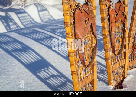 Dettaglio del legno vintage Bear Paw racchette da neve con rilegatura in pelle nella neve con ombra Foto Stock