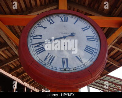 Un vecchio orologio rosso in corrispondenza di una stazione ferroviaria con numeri romani e chiudere fino,Cuba Foto Stock