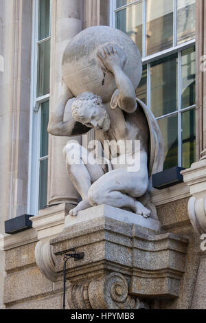 Una scultura di un uomo che porta una sfera sulla sua schiena, sulla facciata di un edificio nella città di Londra, Regno Unito. Foto Stock