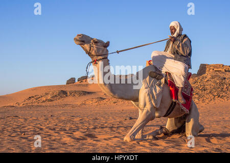 Il governo di Khartoum, Sudan - 19 DIC 2015: Cameleer posa con il suo cammello all'alba davanti alle piramidi. Foto Stock