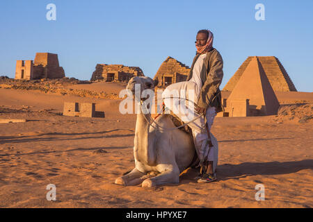 Il governo di Khartoum, Sudan - 19 DIC 2015: Cameleer posa con il suo cammello all'alba davanti alle piramidi. Foto Stock