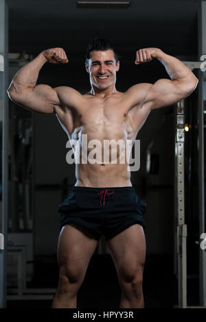 Ritratto di un giovane uomo Fit mostra anteriore doppia bicipite pongono - Atletico muscolare Bodybuilder Modello di Fitness in posa Foto Stock