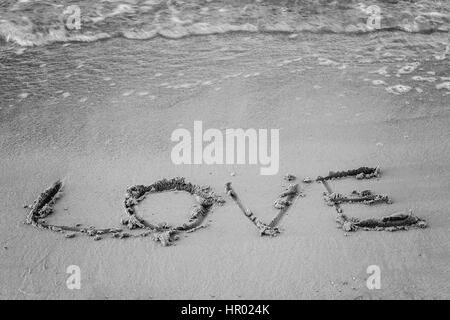 Sulla sabbia della parola scritta e il suo amore lava onda, in bianco e nero. Foto Stock
