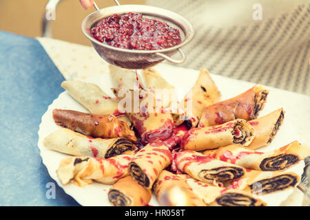 Capellaccio ripieno con semi di papavero sulla piastra bianca. Involtini primavera. Donna colata di sciroppo di lampone. Cooking per colazione. Frittelle ripiene Foto Stock