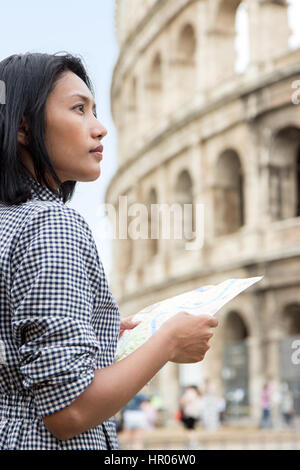 Turisti asiatici in un tour del centro storico di Roma. La donna a studiare la mappa della città vicino al Colosseo, Roma, Italia. Foto Stock