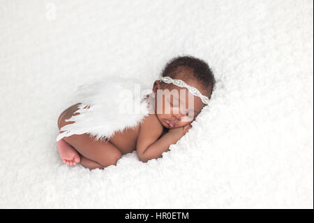 Ritratto di un mese, dormendo, neonato, bambina. Indossa una fascia di strass, feather ali d'angelo, e dormire su una coltre bianca. Foto Stock