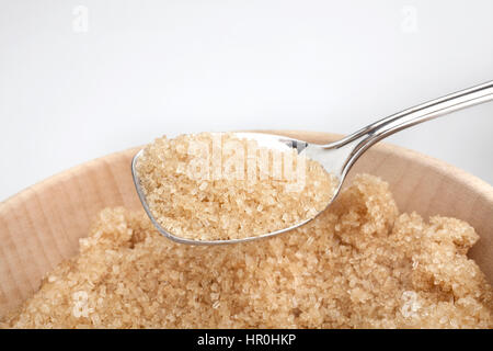 Cucchiaio d'argento pieno di zucchero di canna sulla ciotola di legno Foto Stock