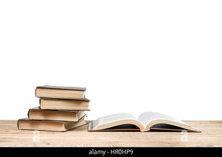 Libro aperto vicino alla pila di libri che giace su di un tavolo di legno isolato su sfondo bianco Foto Stock