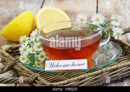 Benvenuti a casa carta con la tazza di tè camomilla e freschi di fiori di camomilla Foto Stock