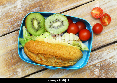 Pranzo al sacco marrone con sandwich di formaggio, pomodori ciliegia e due metà di kiwi Foto Stock