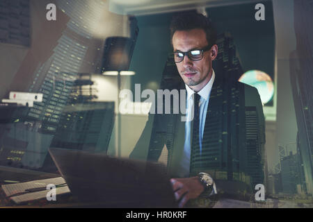 Imprenditore concentrato lavorando in ufficio di notte, grande città la concezione di business Foto Stock