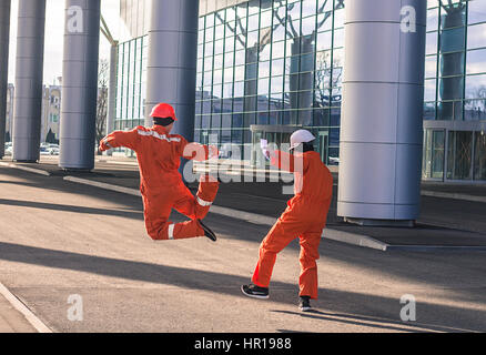 Vista posteriore di felice costruttori in rosso uniforme a piedi. All'aperto orizzontale shot. Foto Stock