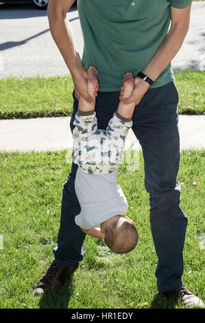 Padre holding baby capovolto Foto Stock