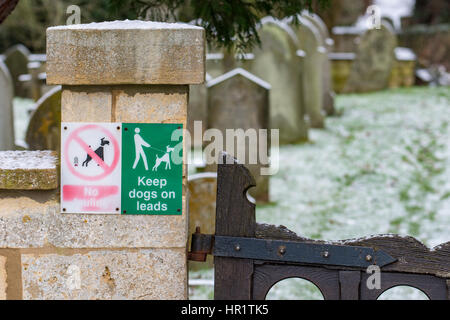 Tenere i cani in segno di piombo in corrispondenza di un ingresso alla chiesa di San Lorenzo cimitero, Mickleton, Gloucestershire Foto Stock