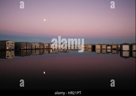 Il Boathouse riflessioni su righe lungo il fronte mare di Everett Marina con il sorgere della luna. Foto Stock