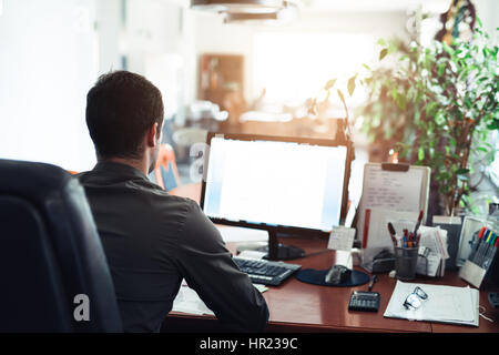 Specchietto di un imprenditore incentrata sul lavoro mentre seduti ad una scrivania in un ufficio con un computer Foto Stock