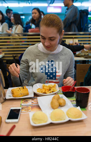 Ragazza mangia dim sum e involtini primavera in stella Michelin ristorante fast food in Hong Kong Foto Stock