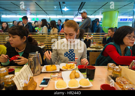 Ragazza mangia dim sum e involtini primavera in stella Michelin ristorante fast food in Hong Kong Foto Stock