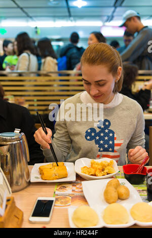 Ragazza mangia dim sum e involtini primavera in stella Michelin ristorante fast food in Hong Kong Foto Stock