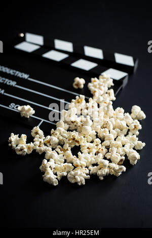 Clapperboard e popcorn su sfondo nero. Foto Stock