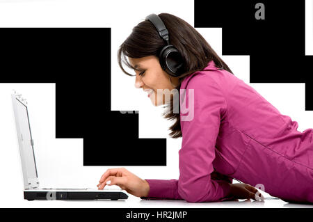 Casual studentessa in viola abbigliamento ascolto di musica mp3 su un computer portatile isolato su uno sfondo bianco Foto Stock