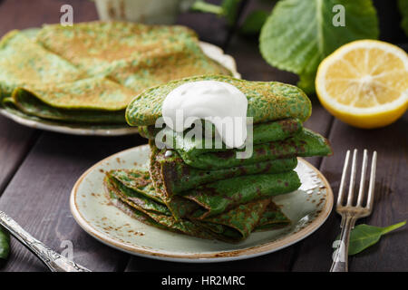 Frittelle di spinaci e panna acida sulla tavola di legno. Foto Stock