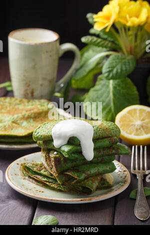 Frittelle di spinaci e panna acida sulla tavola di legno. Foto Stock