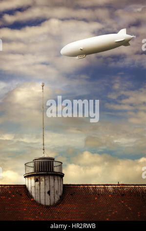 Un blimp sorvola la città contro un drammatico cielo pieno di nuvole al tramonto Foto Stock