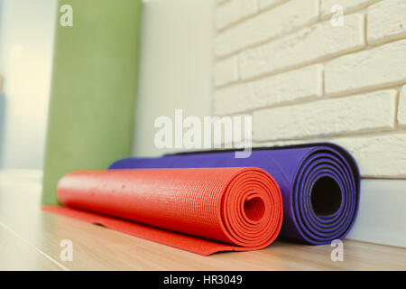 Due Materassini da yoga sono un muro bianco sul pavimento di legno, soft focus. Ginnastica mattutina - sala yoga. Foto Stock