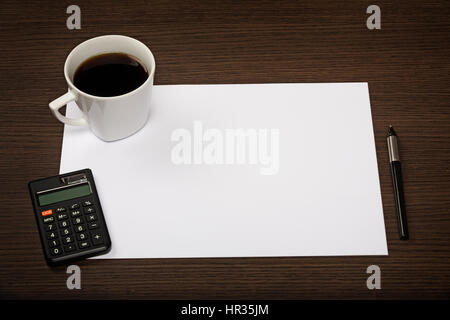 Foglio di carta bianco, calcolatrice, penna e la tazza di caffè sul buio office desk in legno. Foto Stock