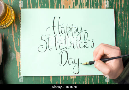 L'uomo la scrittura di un felice St Patrick giorno scheda di calligrafia Foto Stock