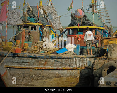 Parte del locale di grandi dimensioni della flotta di pesca spiaggiata presso il porto di Vanakbara su diu isola in Gujarat, India, con le loro catture secchi conditi hanging off rack Foto Stock