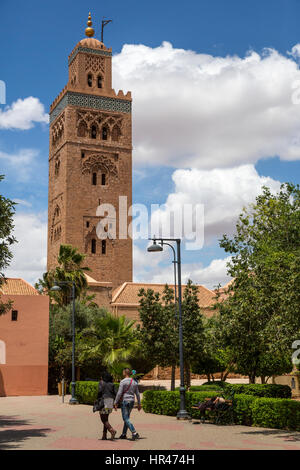Marrakech, Marocco. Giovane Adulto Giovane marocchino a piedi, Minareto di Koutoubia, 12th. Secolo, in background. Foto Stock