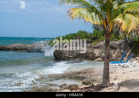 Sedie a sdraio blu che si affaccia sul Mare dei Caraibi, ginup e fiori esotici. Scoprire la ricca cultura, colori, persone e rilassata vibes di Montego Bay. Foto Stock