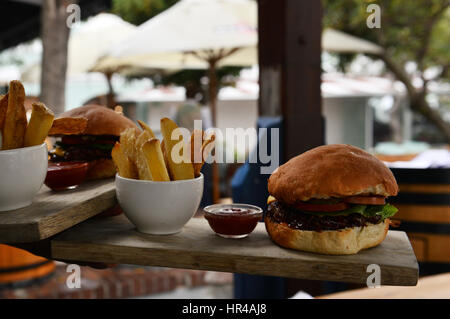 Una succosa cheeseburger servita con home patatine fritte fatte. Foto Stock