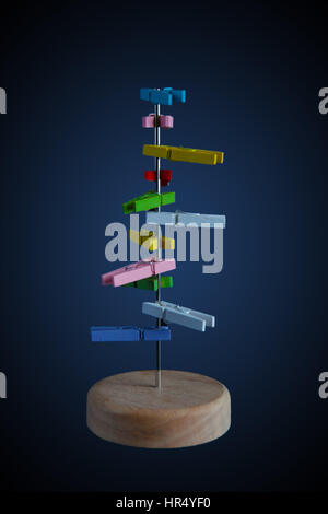 Piccole colorate picchetti di legno su un palo su sfondo scuro Foto Stock