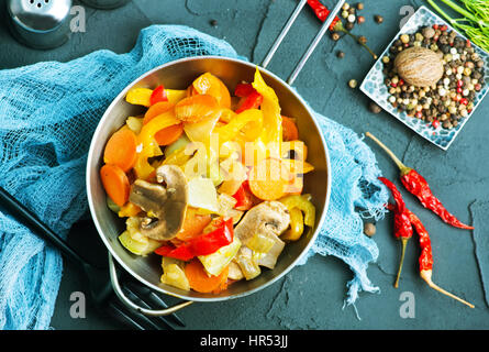 Verdure fritte in un recipiente e su un tavolo Foto Stock