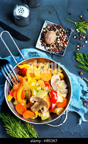 Verdure fritte in un recipiente e su un tavolo Foto Stock