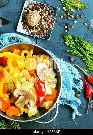 Verdure fritte in un recipiente e su un tavolo Foto Stock