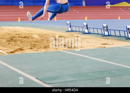 Sportive un salto nella buca di sabbia sul salto triplo concorrenza in pista e sul campo campionato Foto Stock