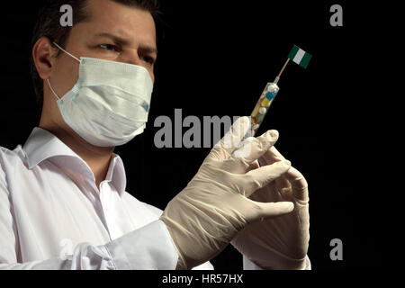Giovane uomo come un medico dà un medico di iniezione a bandiera nigeriana su sfondo nero Foto Stock
