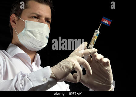 Giovane uomo come un medico dà una iniezione medica a bandiera cambogiano su sfondo nero Foto Stock