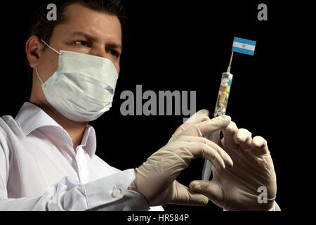 Giovane uomo come un medico dà un medico di iniezione per la bandiera argentina su sfondo nero Foto Stock