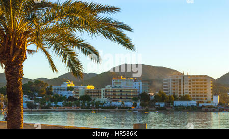 Nel tardo pomeriggio sole cade sulla baia. Sant Antoni de Portmany, Ibiza, Spagna. Alberghi lungo il litorale nella luce del sole dorato, offrire luogo di soggiorno. Foto Stock