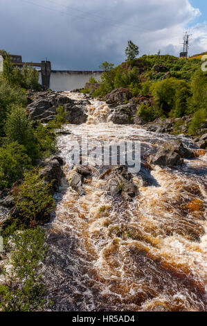 Il fiume Garbh Easan Dhuin nel diluvio witth la diga di Loch Eigheach Gaur serbatoio dietro. Parte del Loch Tummel valley regime. Foto Stock