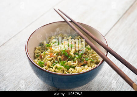 Ciotola di Asian Dried Noodles con bacchette sul tavolo di legno. Foto Stock