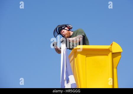 Operaio in un cherry picker lavorando su una bandiera Foto Stock